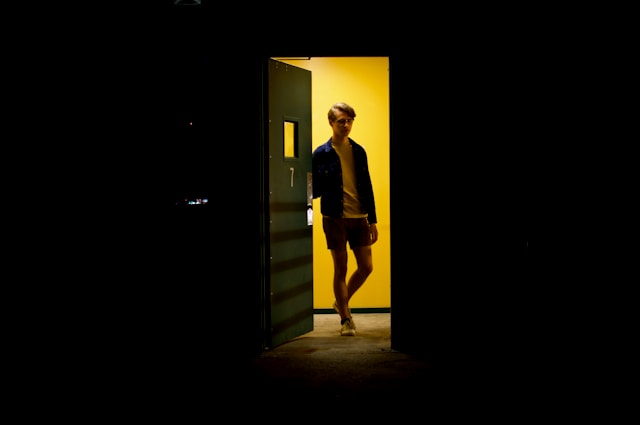 Man standing in illuminated doorway surrounded by darkness representing hope through acceptance therapy