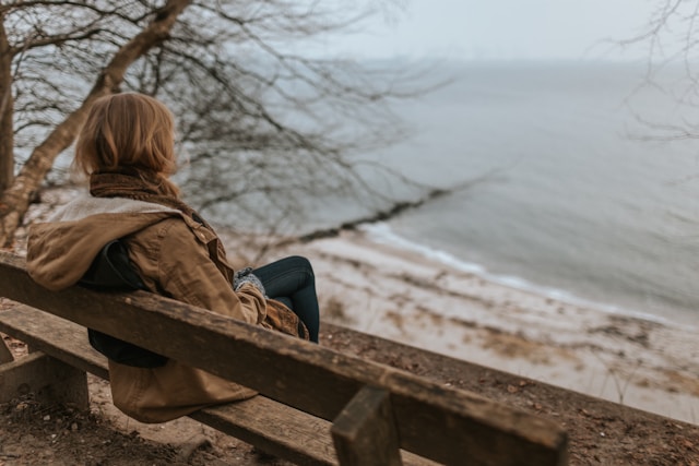 Person relaxing peacefully on a bench looking out at water as part of their anxiety relief routine