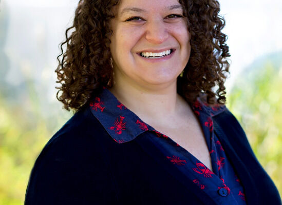 Professional photo of Mindy Rothman, therapist, smiling outdoors in dark top with embroidered details