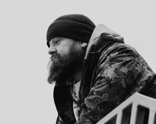 Man in beanie and jacket looking away in deep contemplation