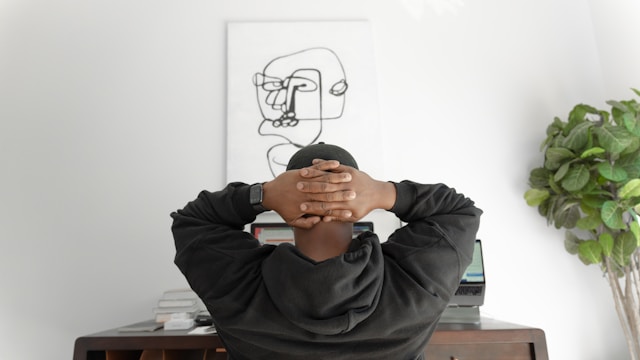 Person sitting at desk with hands behind head showing signs of mental overwhelm