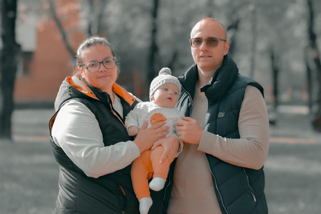 Two parents holding baby outdoors in winter clothing, representing family support during postpartum period
