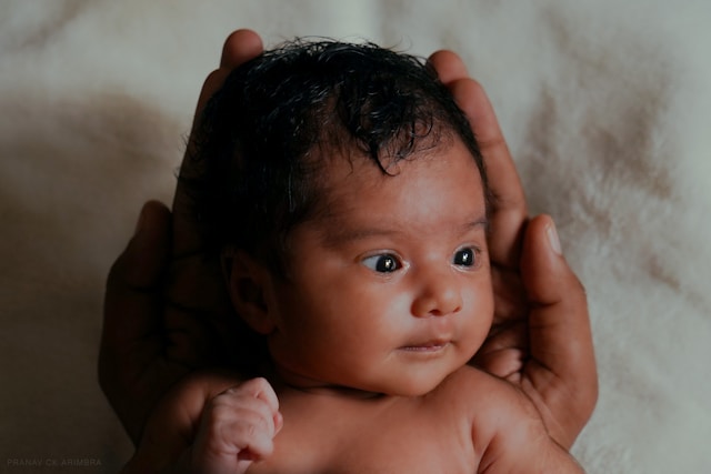 Newborn baby being gently held in parent's hands during early postpartum period