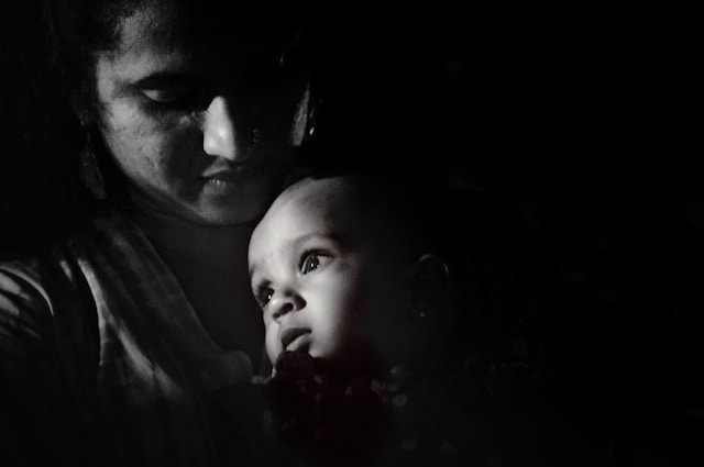 Black and white photo of mother tenderly holding baby, representing postpartum emotional experience