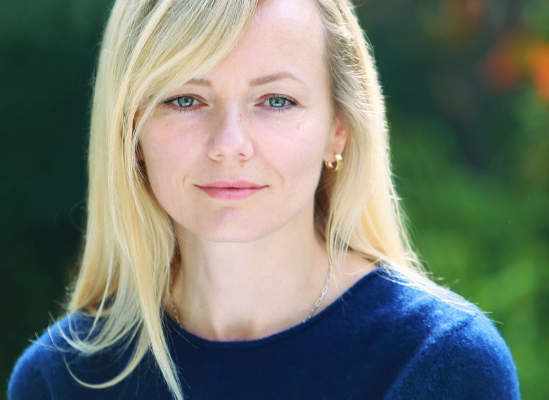 Professional portrait of Bernadetta Zawiejska, therapist, smiling outdoors with greenery in background