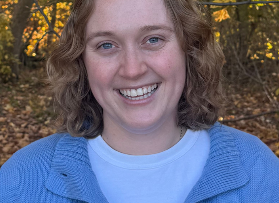 Professional headshot of Brynne Dochterman, therapist, smiling outdoors with fall foliage in background