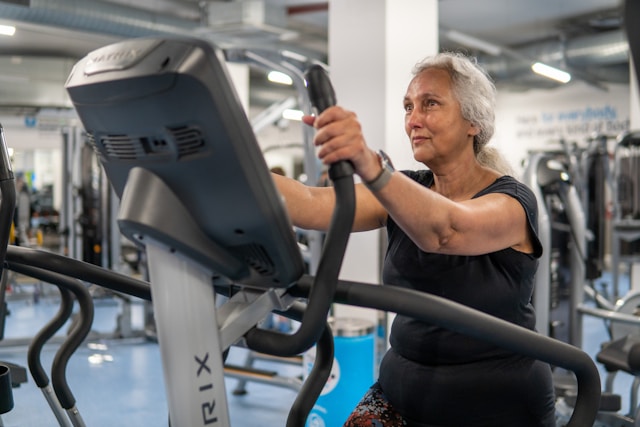 Older woman exercising on a stationary bike at a gym.