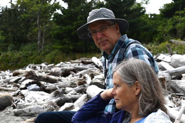 Older couple sitting peacefully together on driftwood at beach
