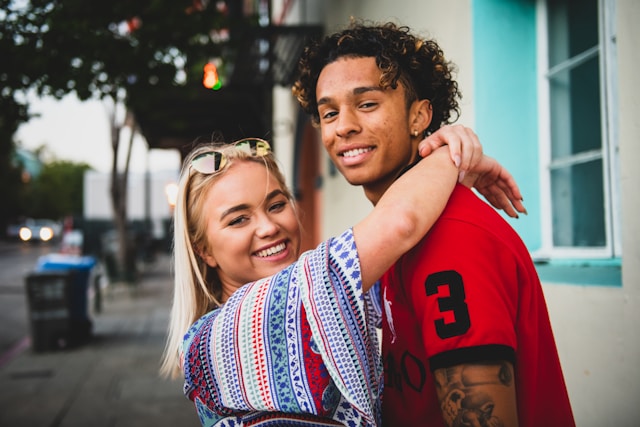 Young interracial couple embracing and smiling on city street