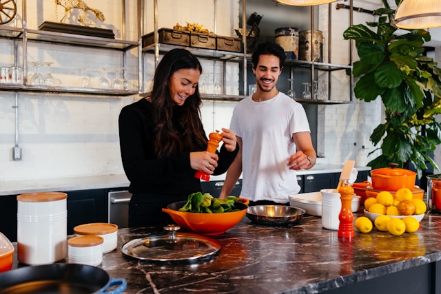 Couple cooking together in modern kitchen, smiling and preparing food