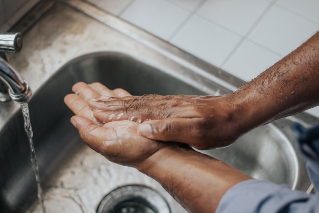 Close-up of hands being washed repeatedly under running water at sink, illustrating contamination OCD compulsion