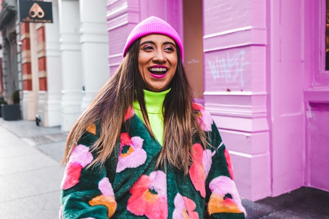 Smiling woman in bright pink hat and colorful sweater expressing joy and confidence after completing OCD therapy