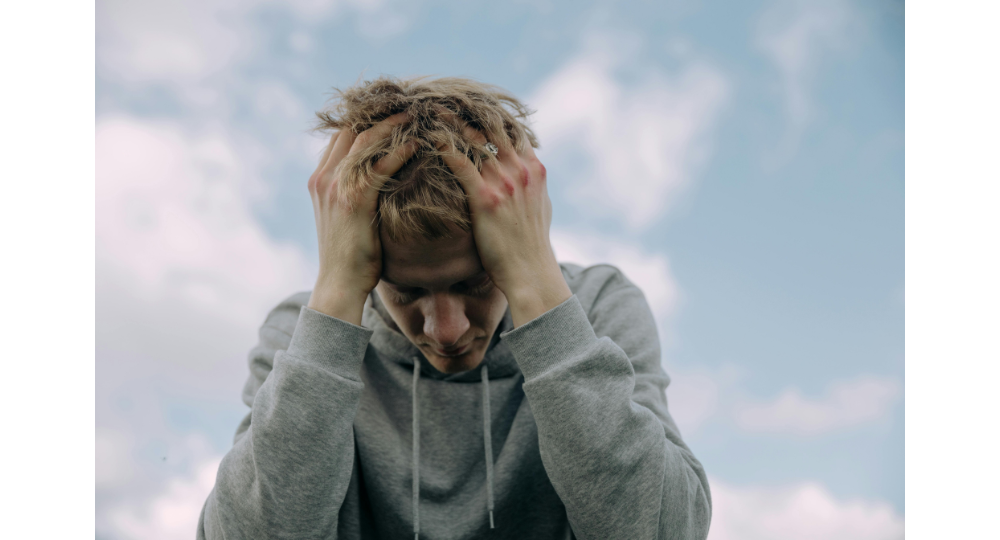 Image of man holding his head in his hands